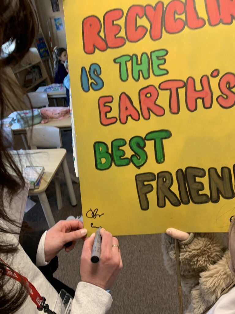 A handpainted sign that reads recycling is the earth's friend