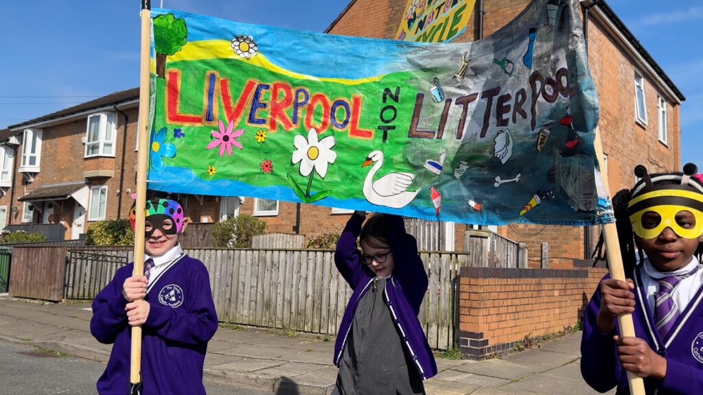 Kids hold up a homemade sign that reads Liverpool not litterpool
