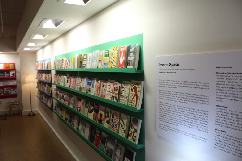 A photos of Dream Space - brightly coloured shelving lined with colourful books arranged so that you can see all the covers. In the foreground there is a sign with some text about Dream Space.